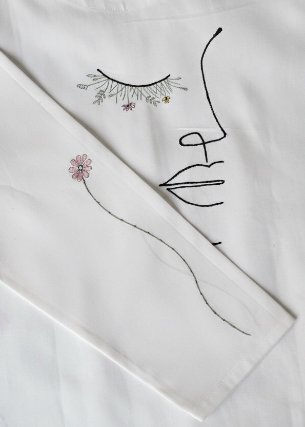 White fabric with black embroidered designs on a light gray background
