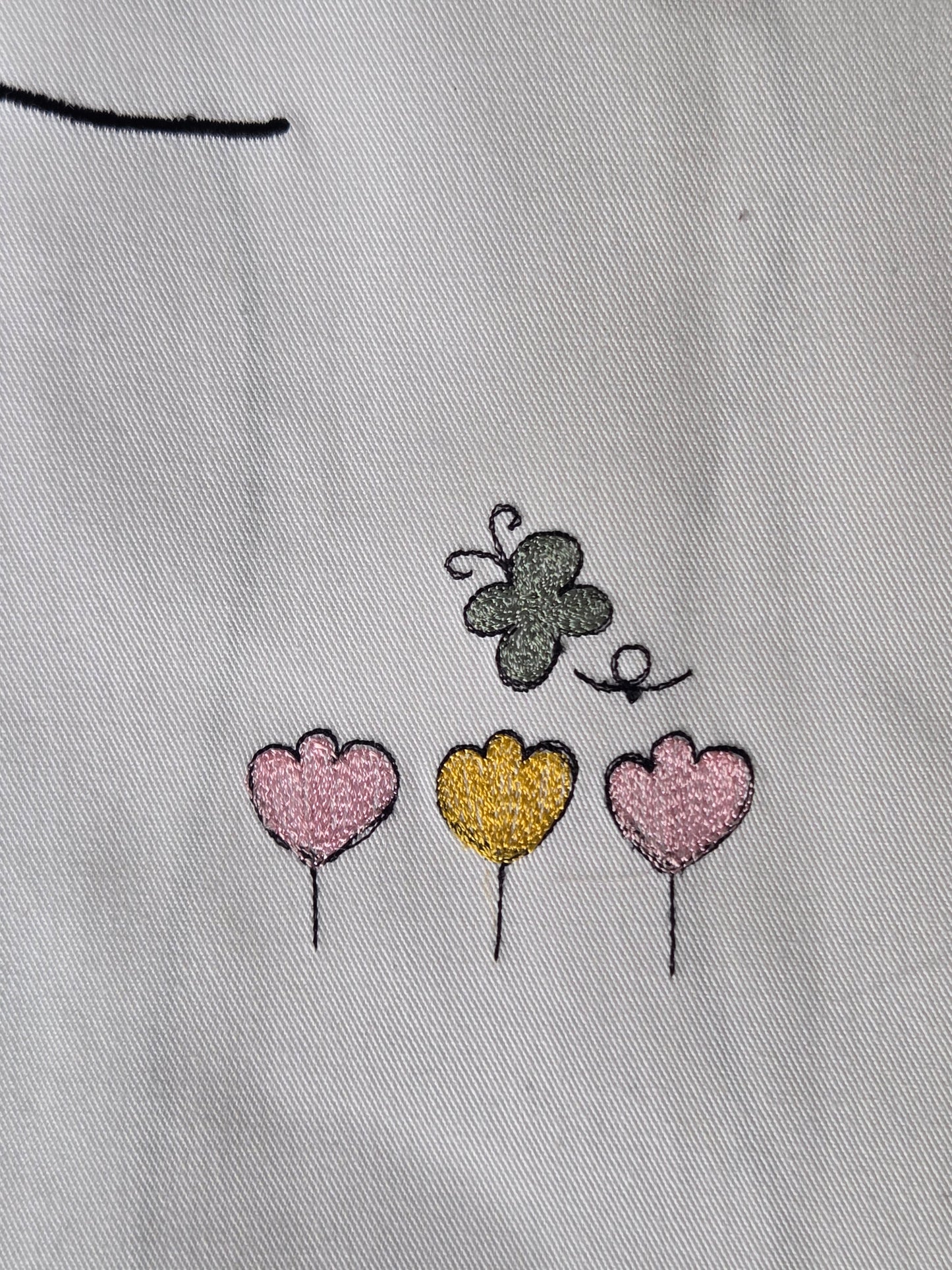 Embroidered butterfly and heart shapes on a light fabric background