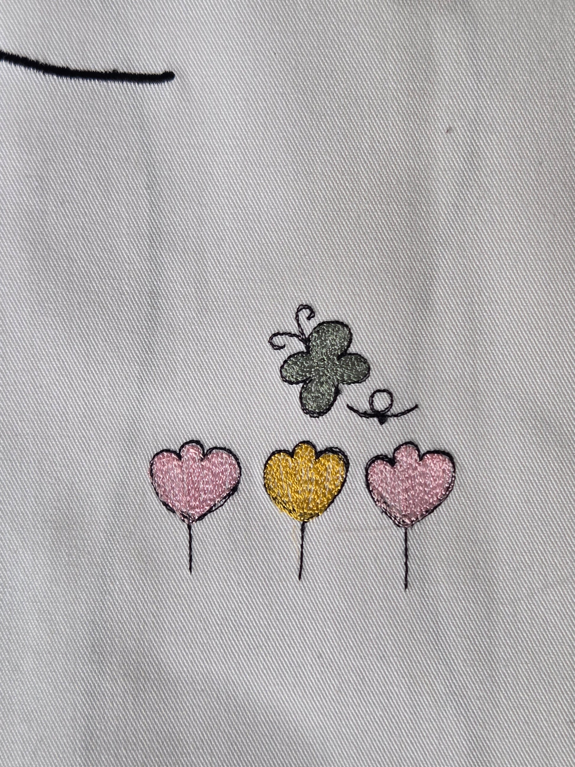 Embroidered butterfly and heart shapes on a light fabric background
