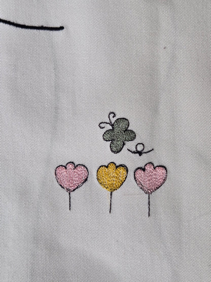 Embroidered butterfly and heart shapes on a light fabric background