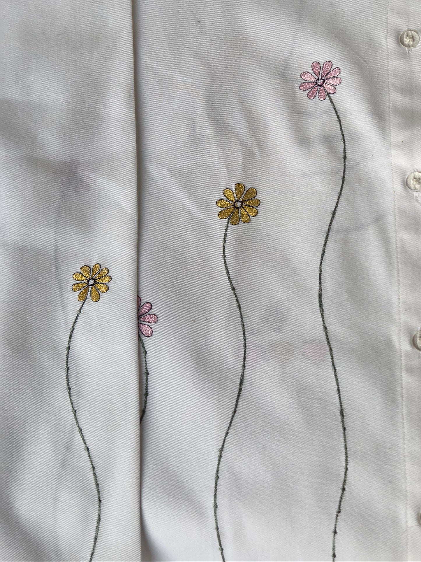Close-up of a white shirt with floral embroidery on a plain background