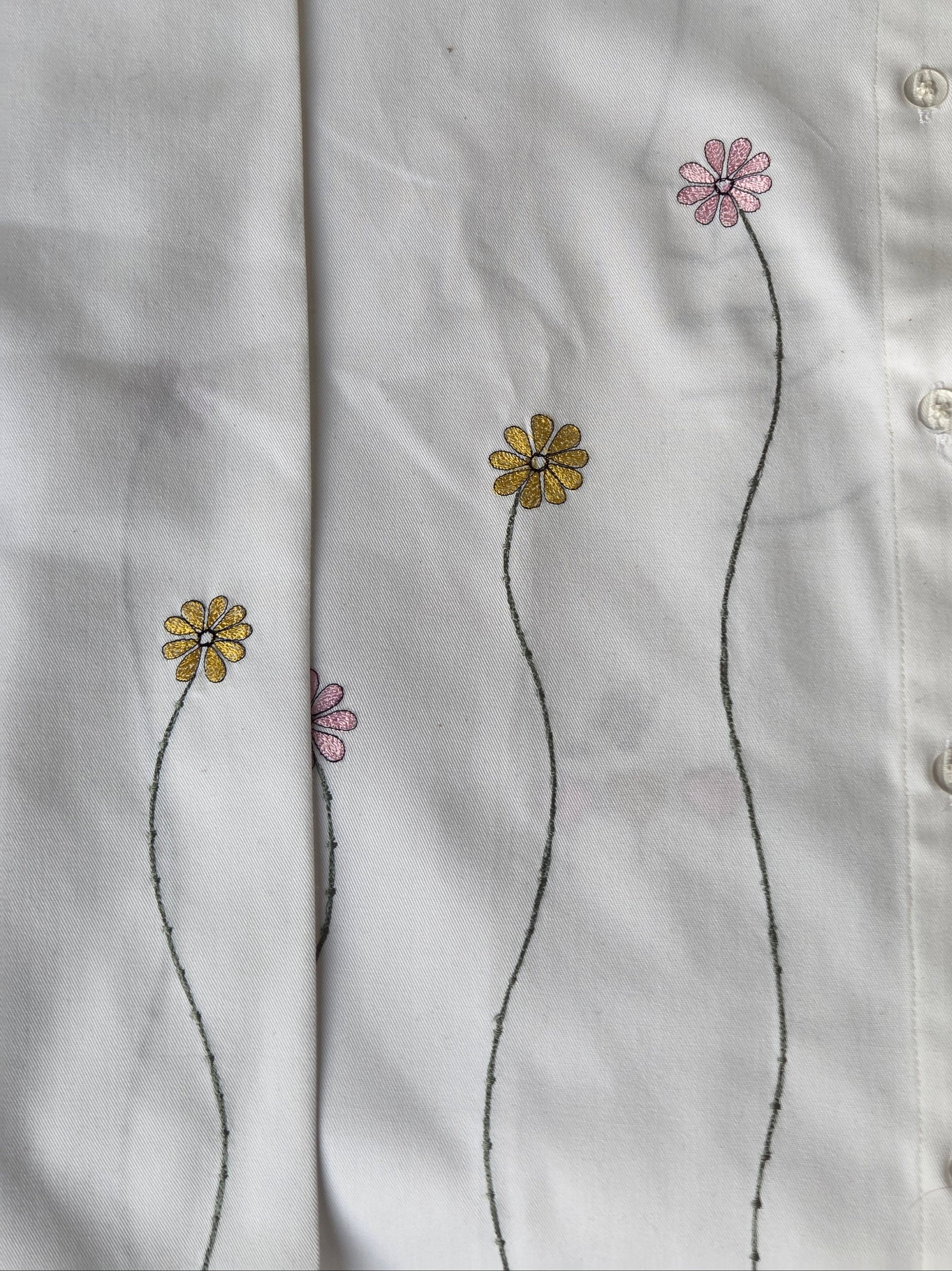 Close-up of a white shirt with floral embroidery on a plain background