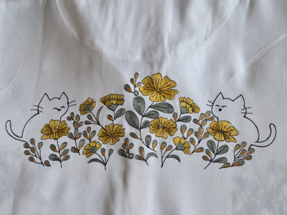 Embroidered design of cats and flowers on a white fabric background